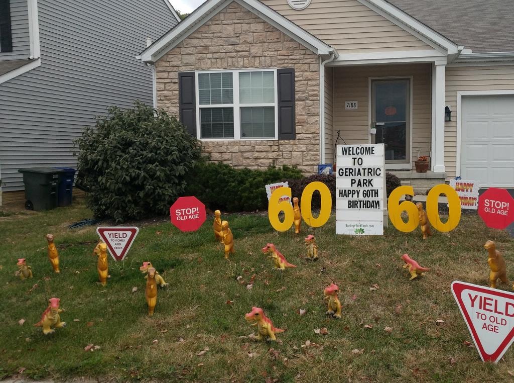 Lawn decorated with dinosaurs and 60th birthday signs