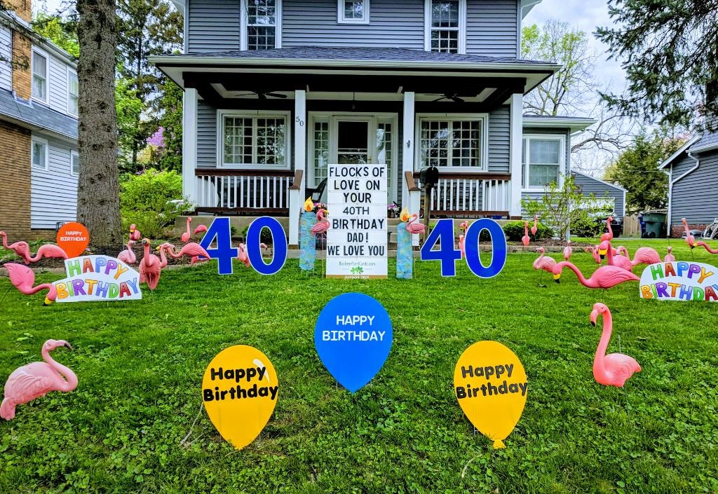 Gray two-story home with flamingos blue 40 signs and balloons for Dad's 40th birthday