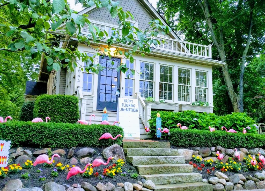 Charming cottage home at dusk with pink flamingos and candles for a flocking un-birthday