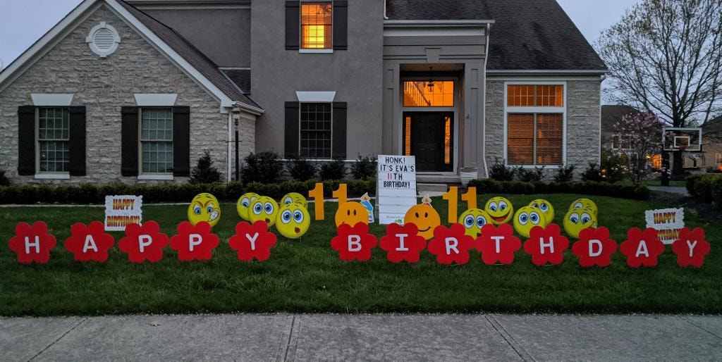 Stone home with smiley face and flower letter yard signs for Eva's 11th birthday
