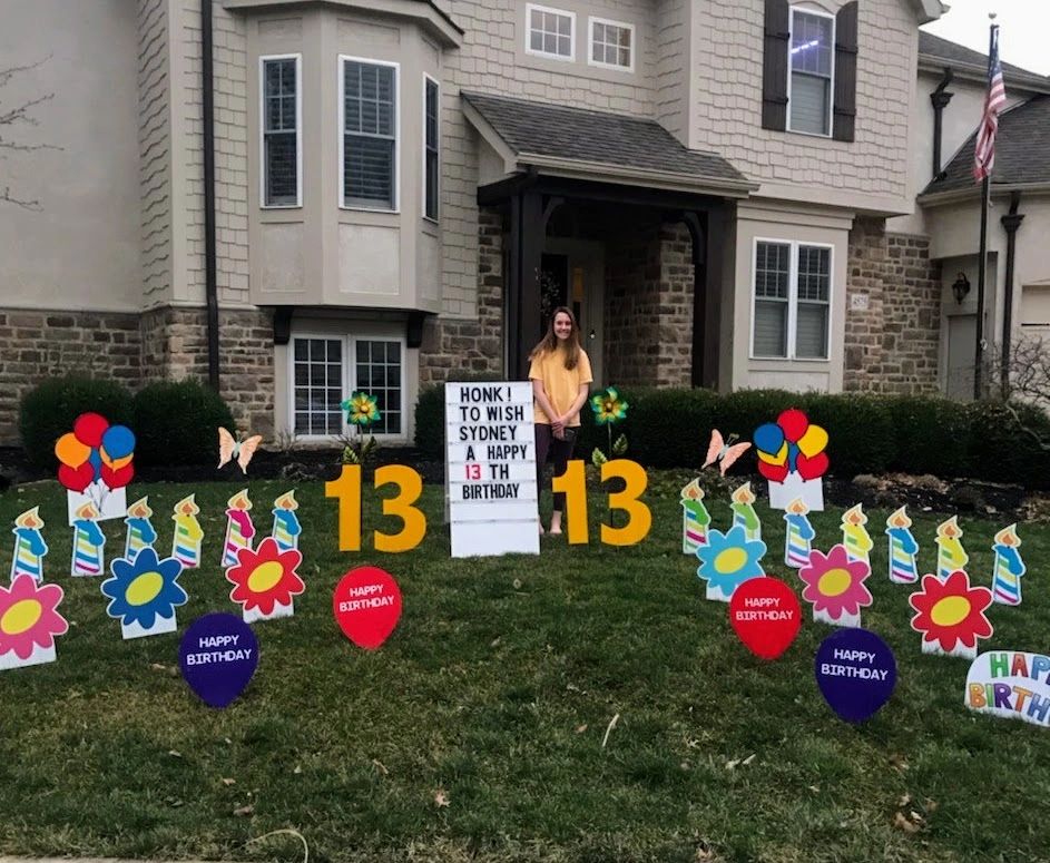 Person holding honk sign at 13th birthday yard card display